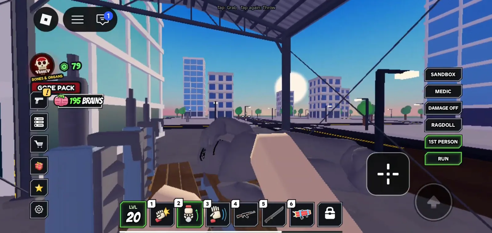 Under a Sawmill-style roof in Ragdoll Reality the same tap grab and throw banner appears above a prone dummy on a wooden carriage with mobile sandbox toggles on the right.